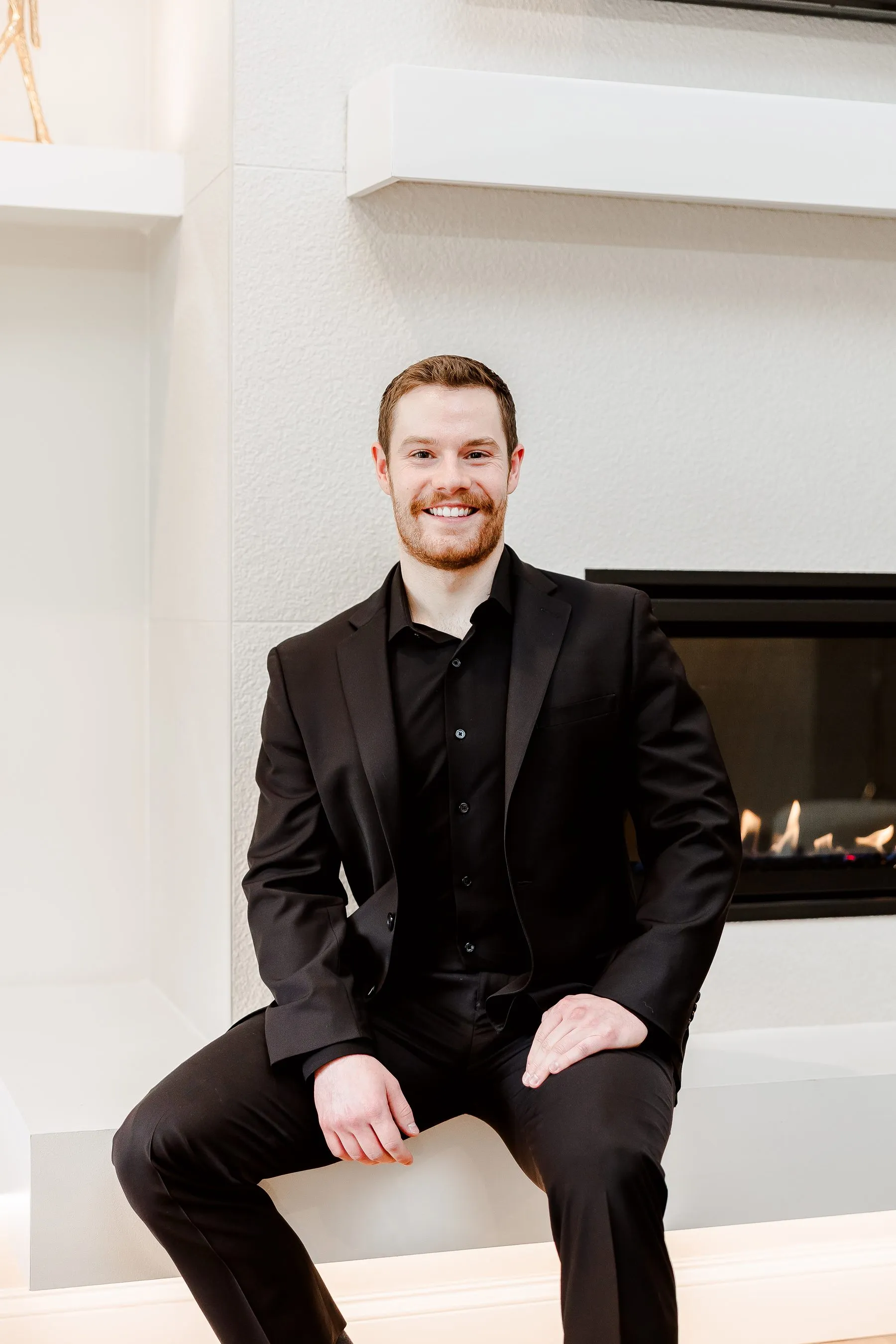 Jacob Peistrup, founder of Formbreak, a St. Louis AI SEO agency, seated on a fireplace hearth in a dark suit
